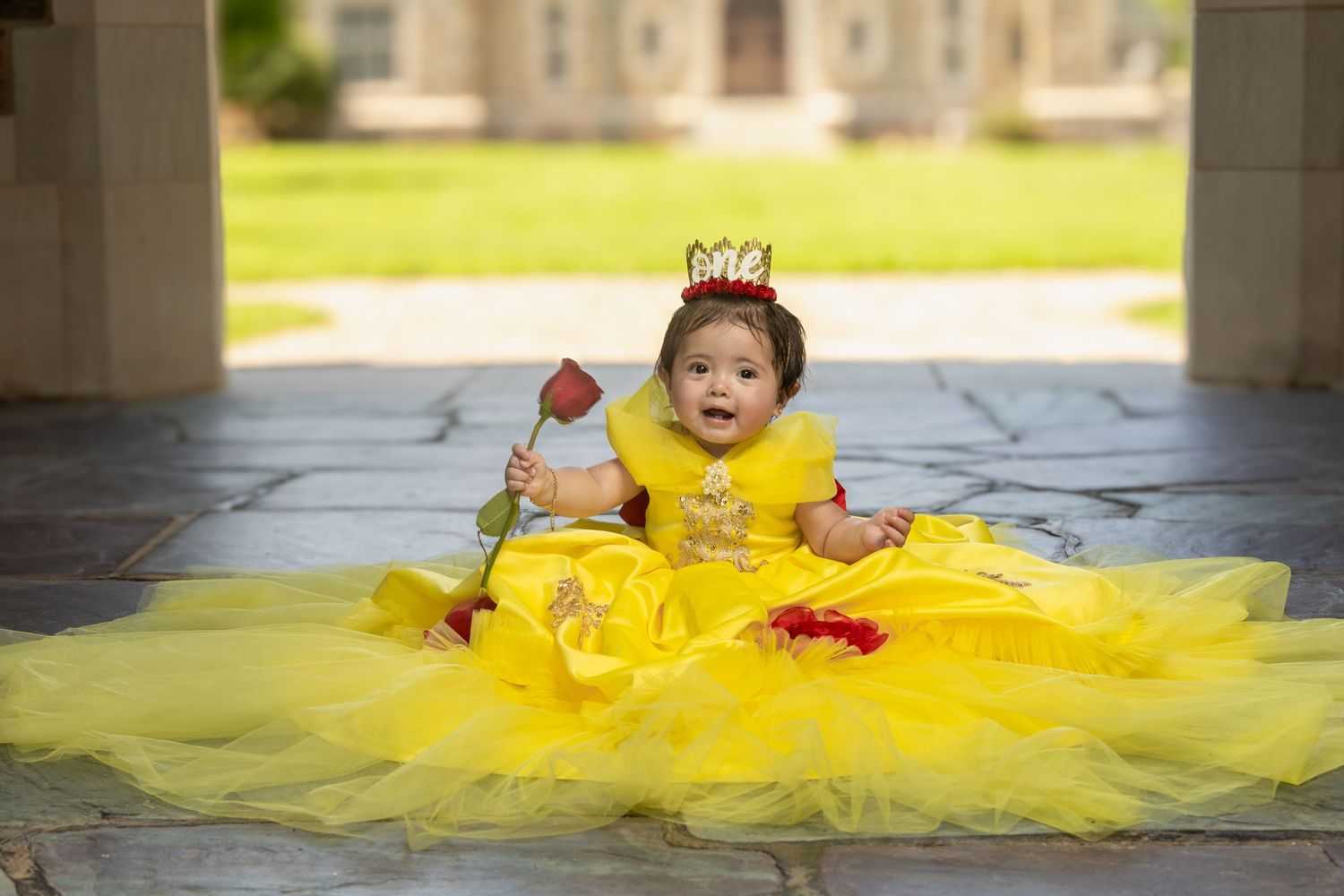 Joyful moment captured of a toddler wearing a bright yellow princess dress and tiny crown.