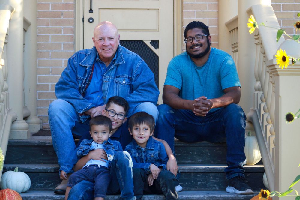 Group sits on brick building steps with pumpkin decorations during fall season.