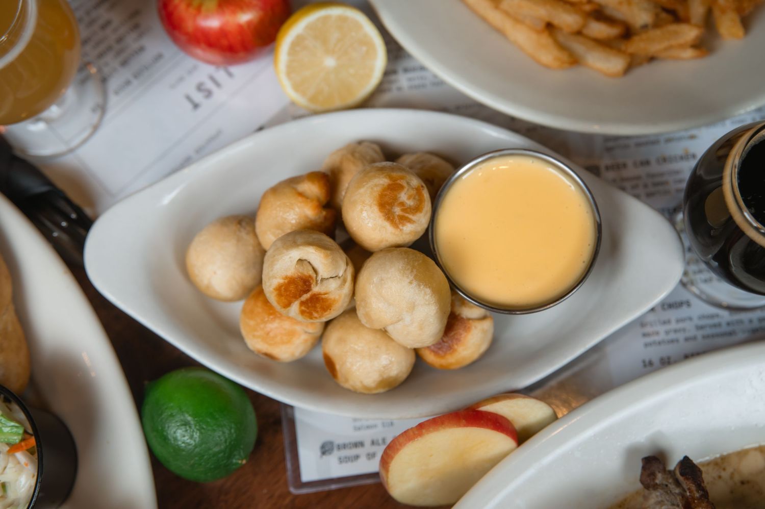 Golden fried mushrooms served with creamy cheese dipping sauce, accompanied by fresh fruit and fries on a restaurant table.