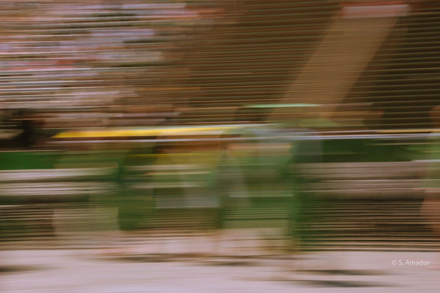 Abstract motion blur photography showing streaks of green, brown, and yellow colors.