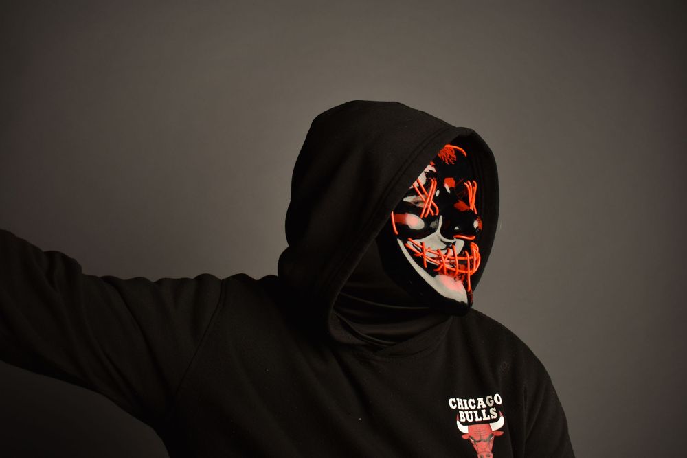 Person wearing a black Chicago Bulls hoodie and illuminated LED Halloween mask with red and white design.