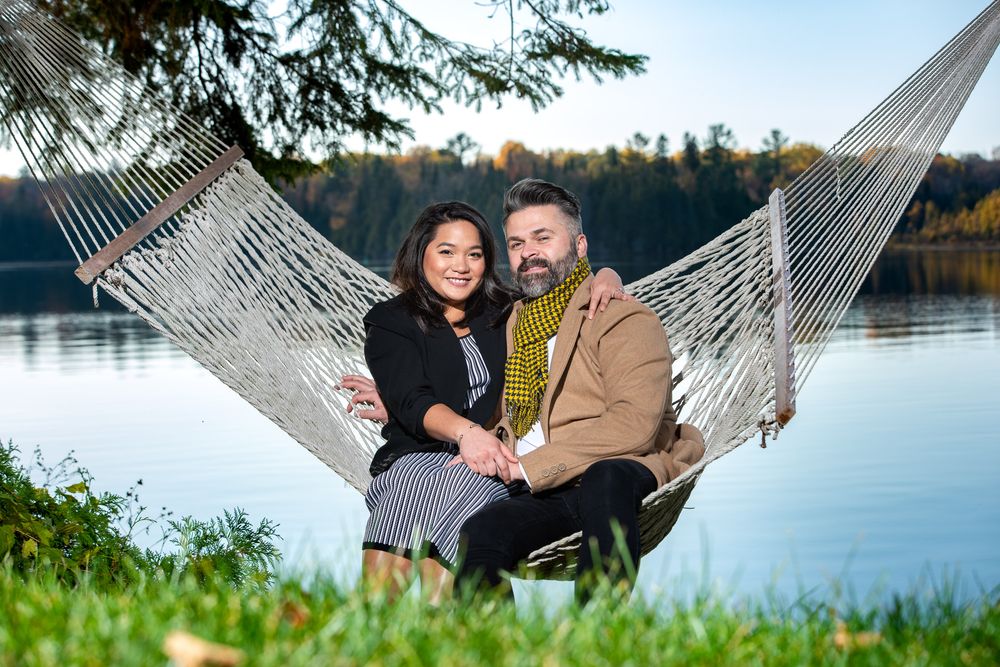 Couple sitting together on a hammock by a serene lake during autumn.