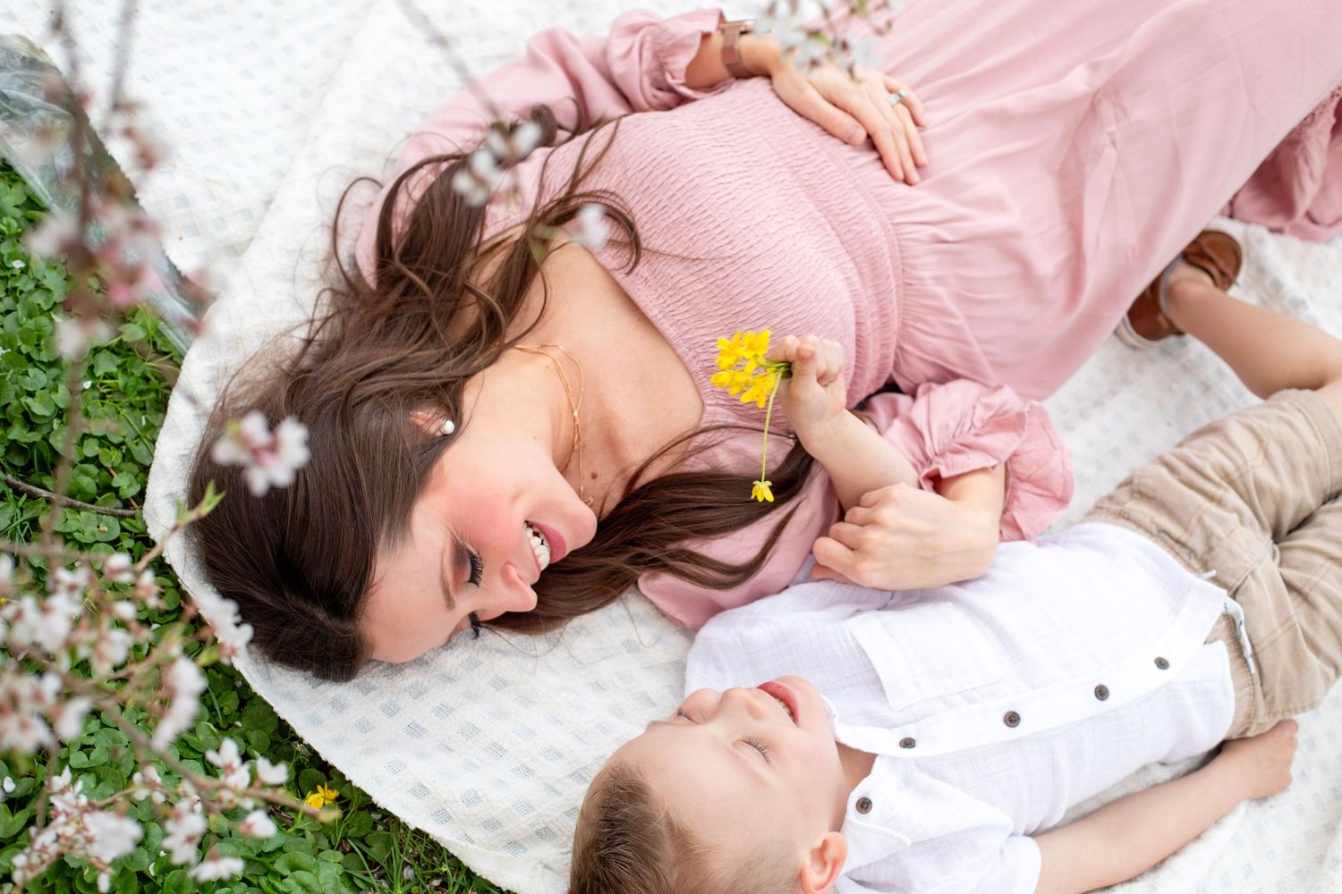 Mom and son laying on picnic blanket in Cincinnati park capturing premium, joyful family portraits for high-end clients