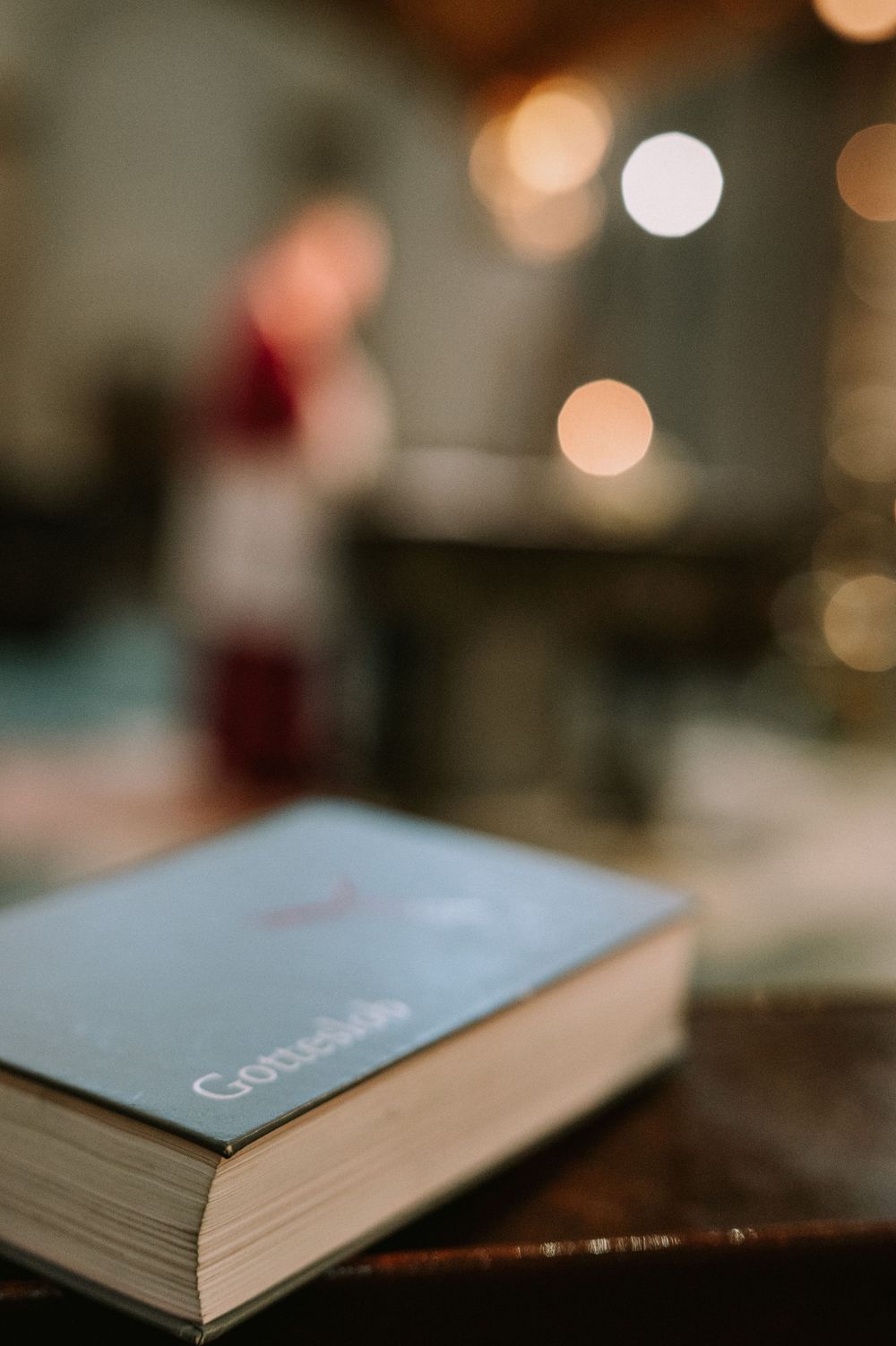 Gesangbuch im Vordergrund mit stimmungsvoll beleuchtetem Kirchenraum im Hintergrund.