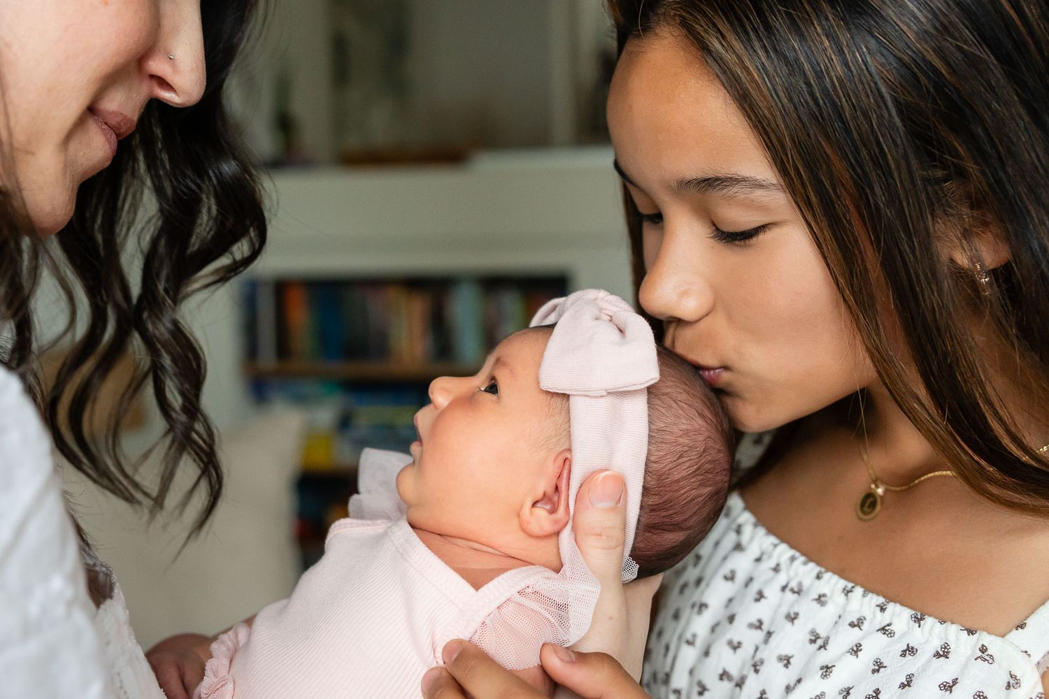 Sister kissing newborn sister.