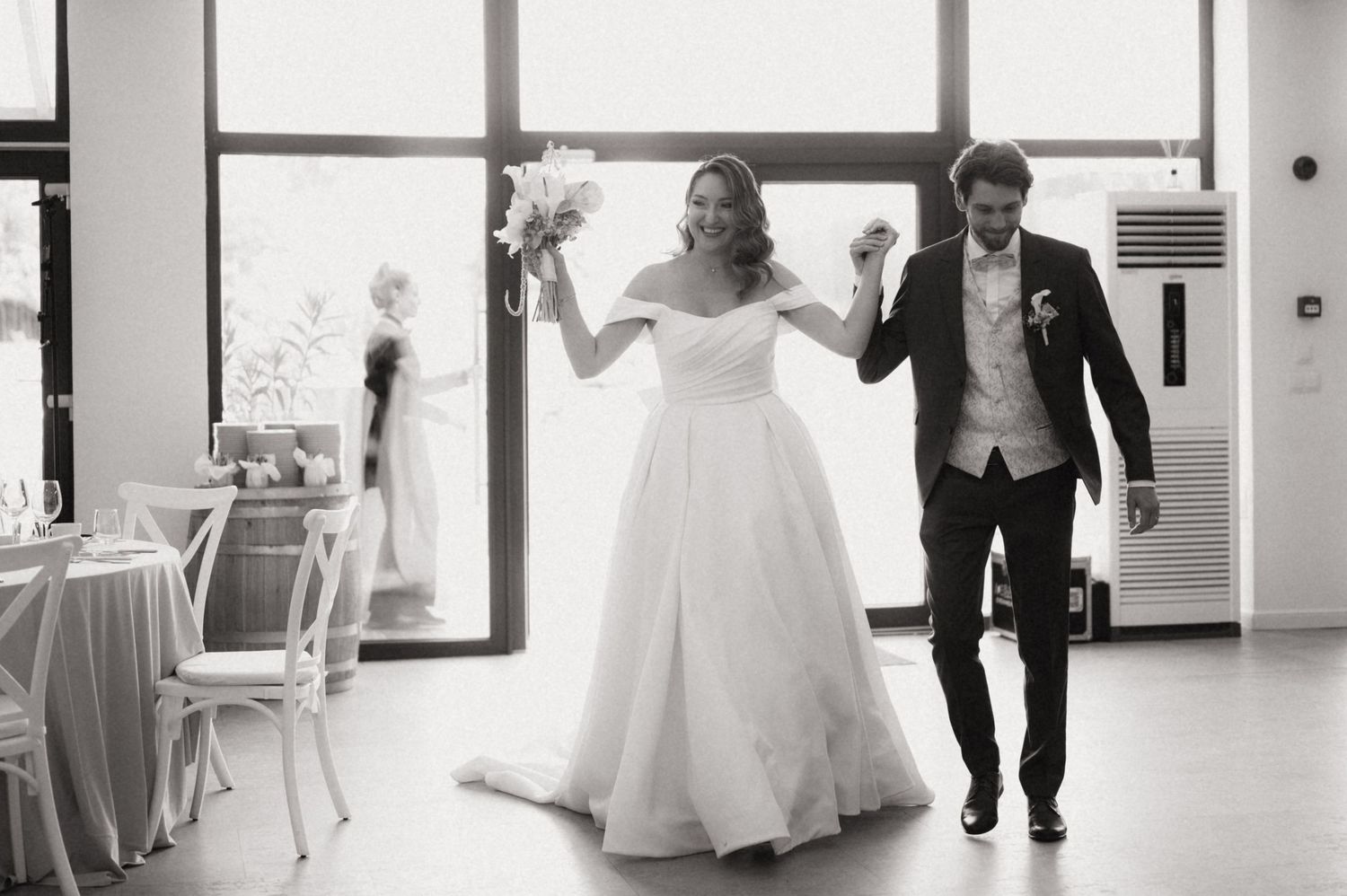 Black and white photo of a bride and groom making a grand entrance at their wedding reception hall.