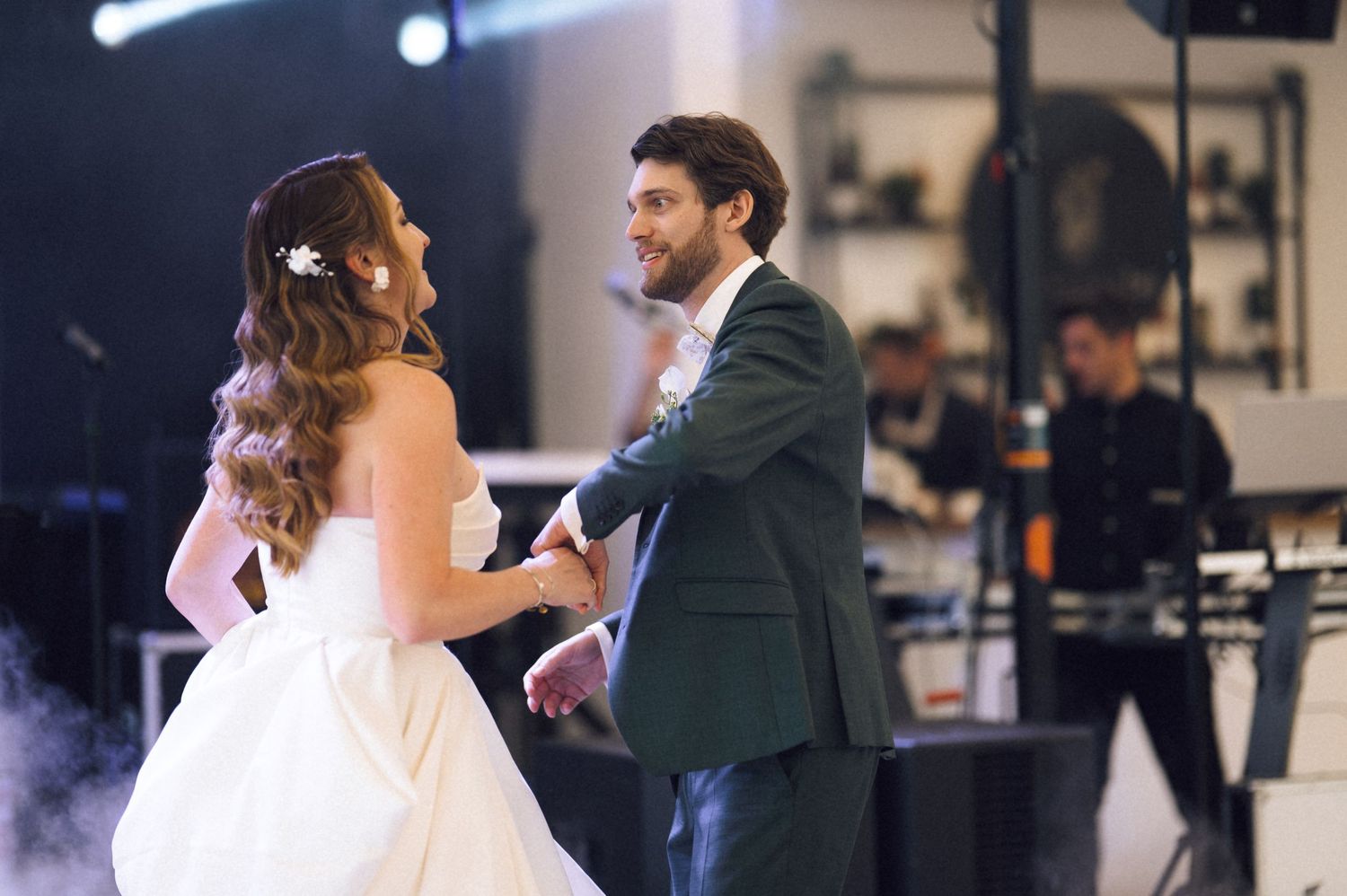 Bride and groom share their first dance at a wedding reception with a live band performing in the background.