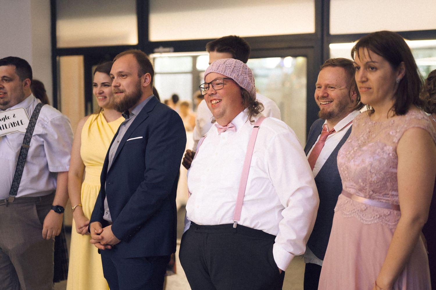 Guests smiling and laughing together at a wedding reception in formal attire.