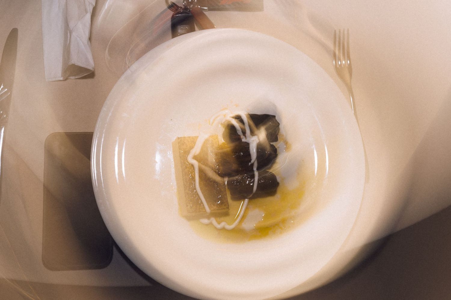 Overhead view of elegant pasta dish with black truffle and butter sauce served on white plate.