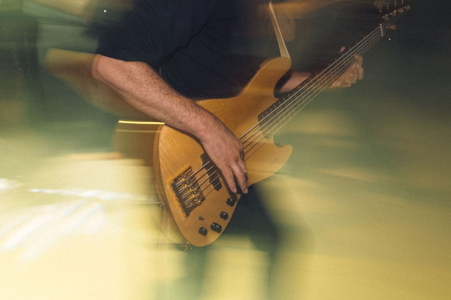 Musician playing a yellow electric guitar on stage with motion blur effect creating dynamic energy.