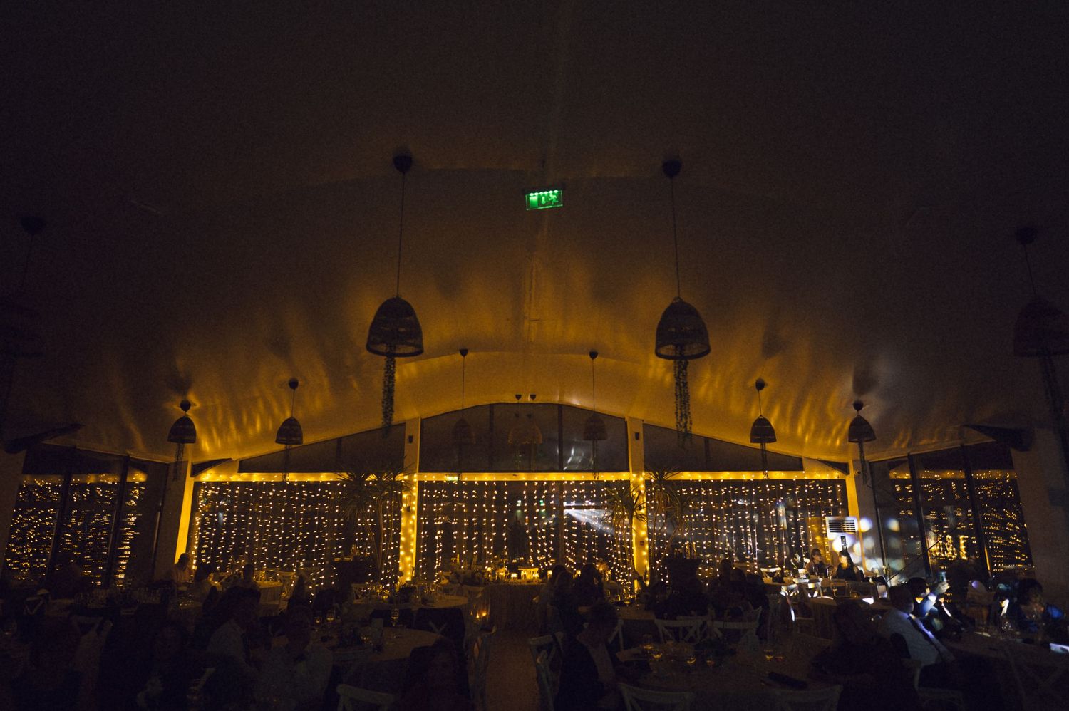 Elegant wedding reception venue with warm golden lighting illuminating arched ceiling and fairy lights.