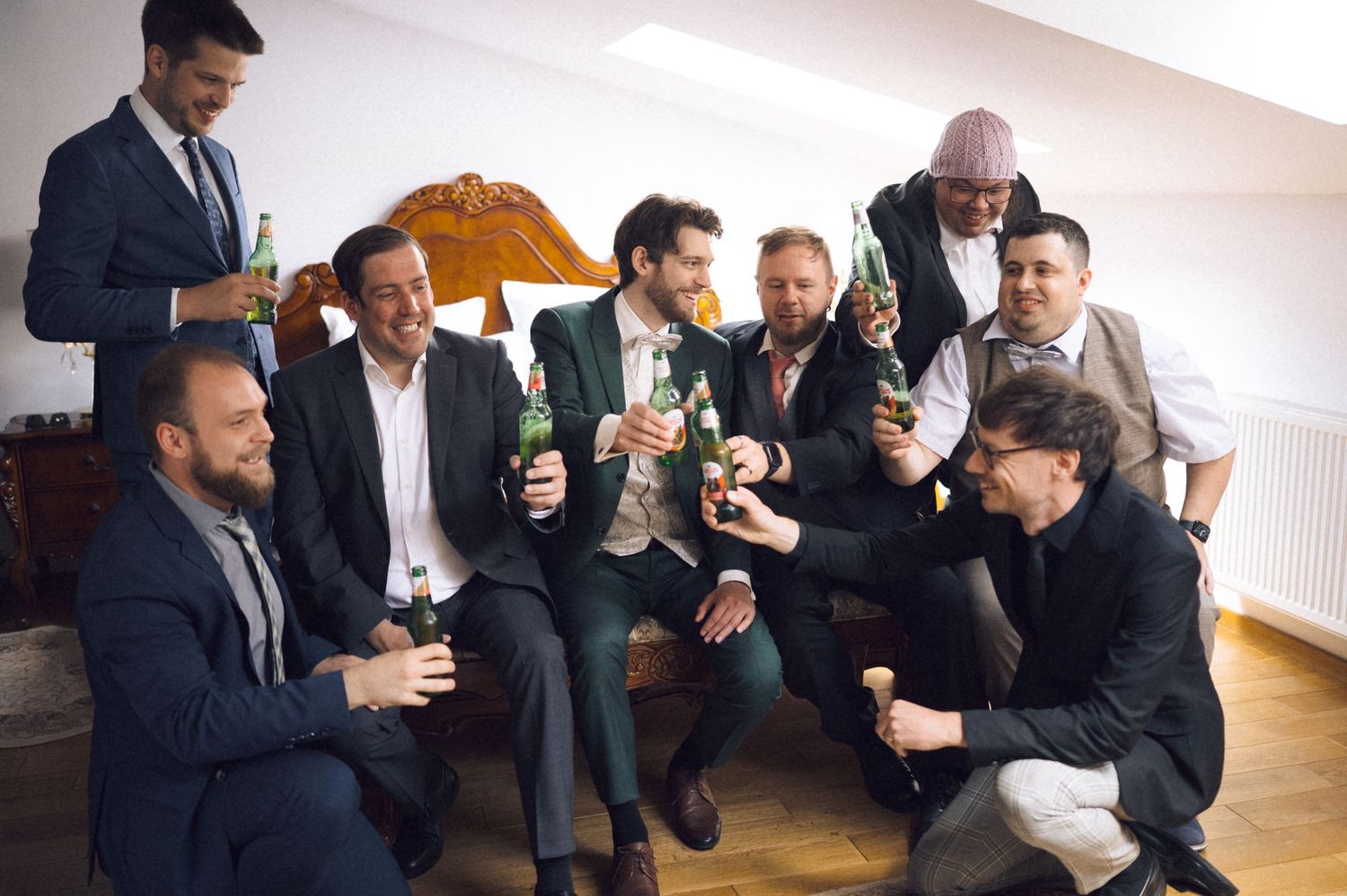 Group of groomsmen celebrating with beer bottles before a wedding ceremony.