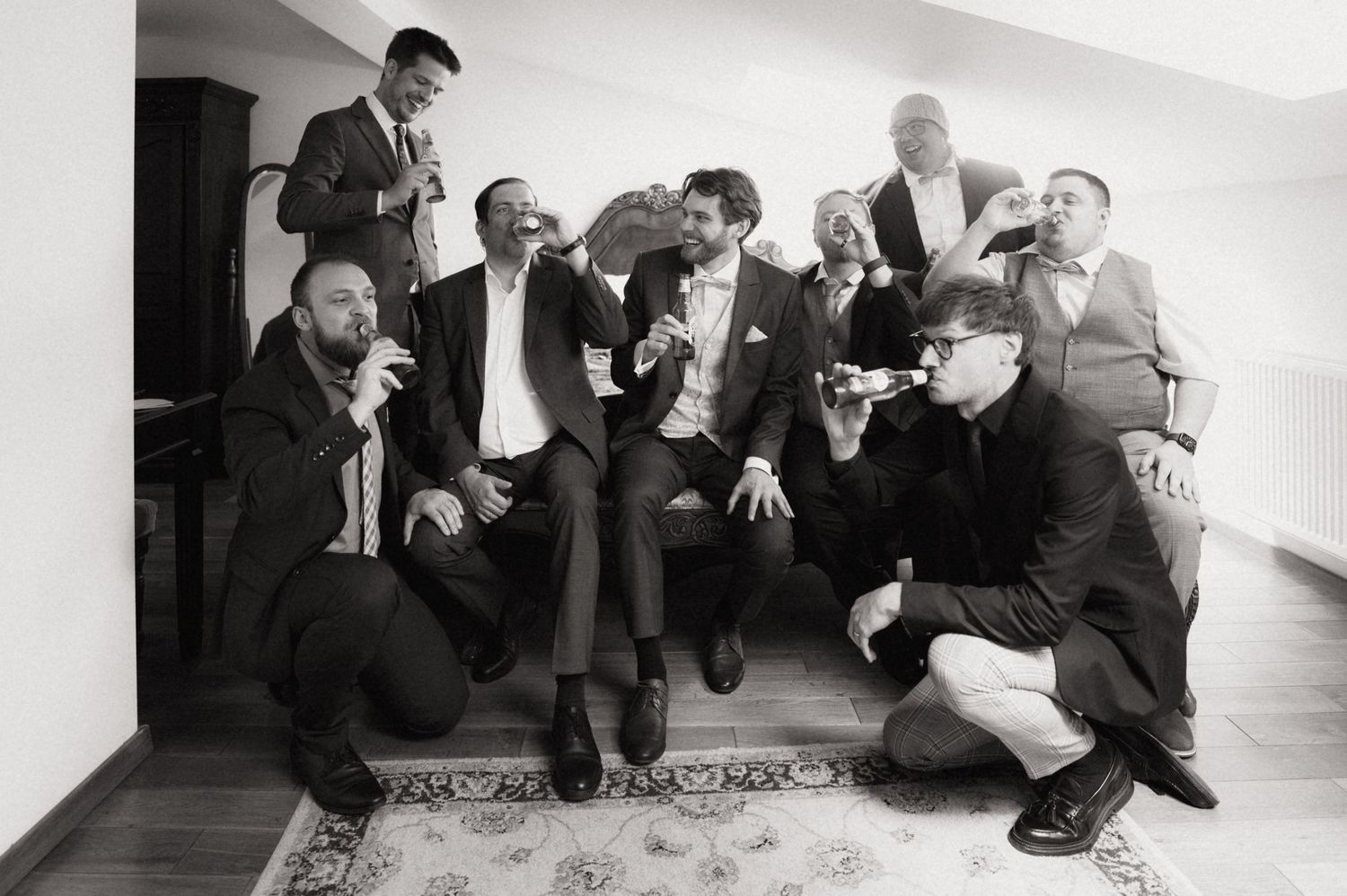 Black and white photo of groomsmen toasting with drinks before a wedding.