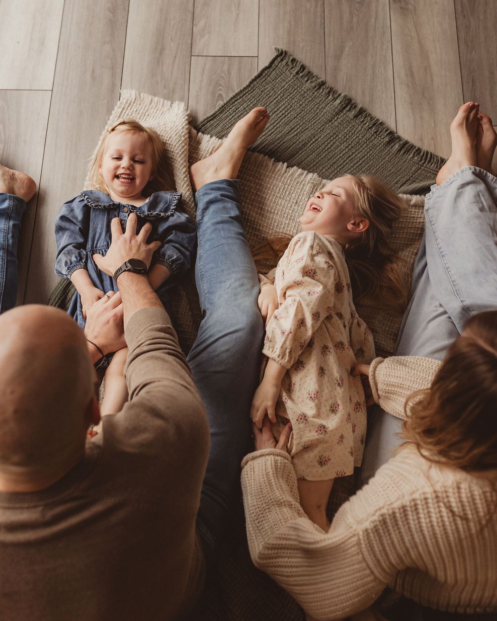 Top view of a happy family of four laughing together while relaxing on the floor.