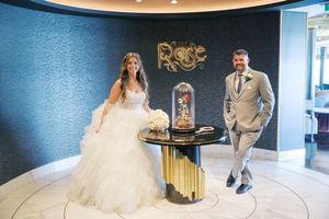 Bride and groom pose by enchanted rose display at The Rose venue on their wedding day.