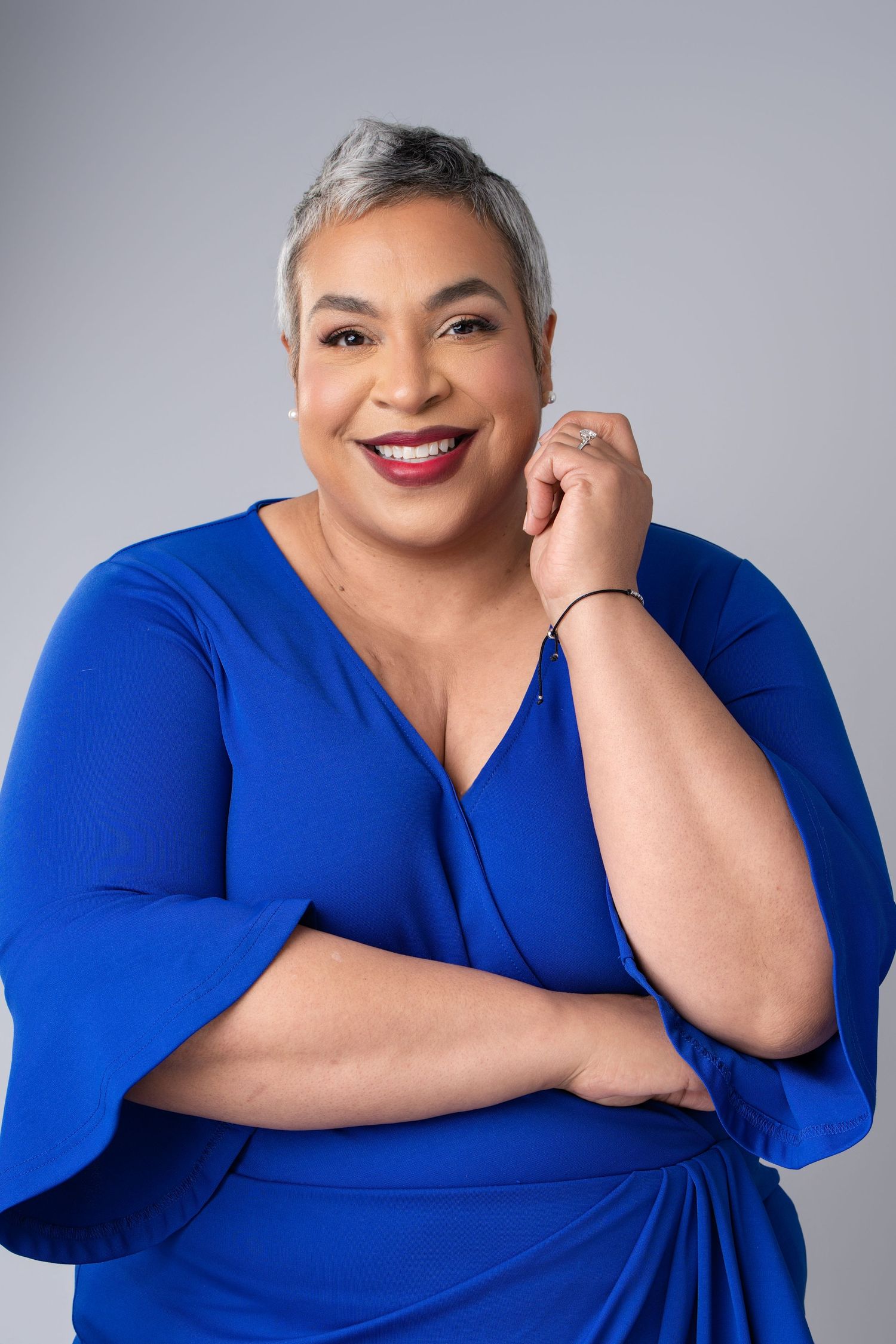 Smiling woman with short gray hair wearing a green top poses for a professional headshot photo.
