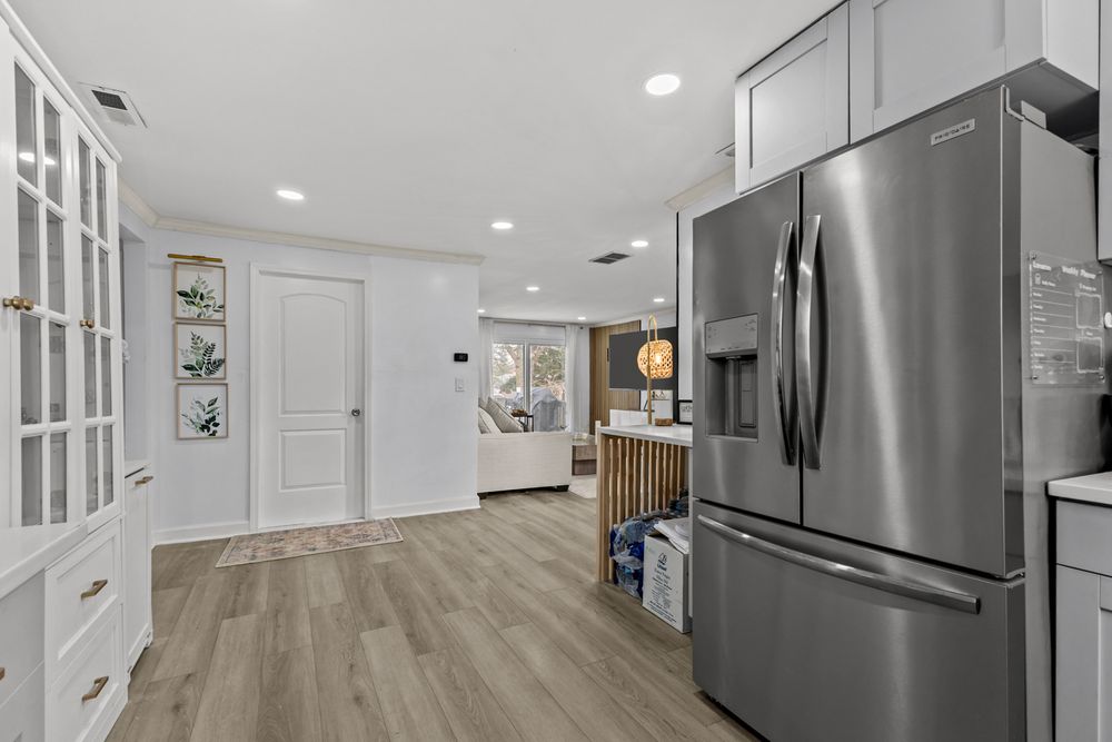 Renovated kitchen with gray cabinetry, large stainless steel French door refrigerator, and light hardwood flooring.
