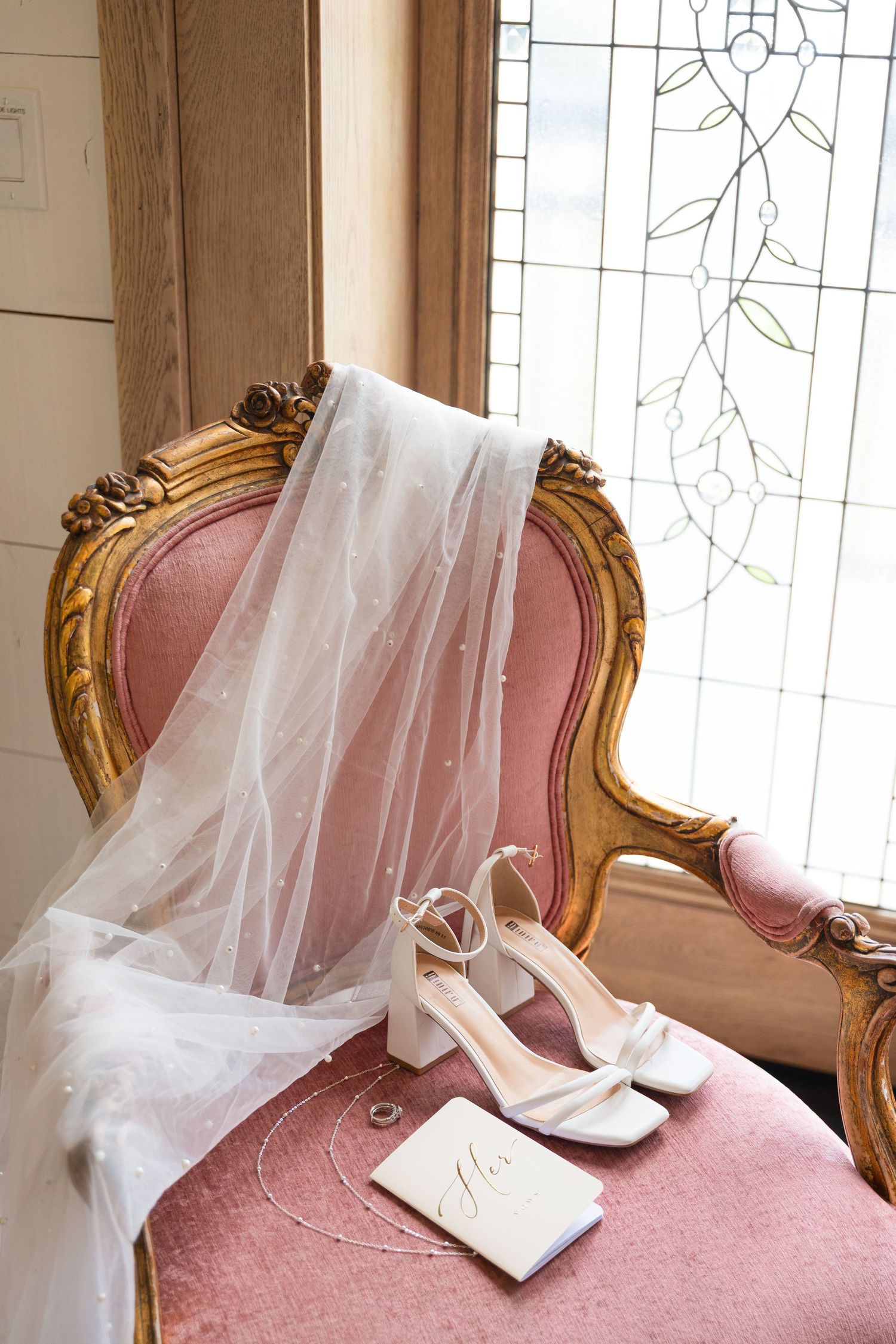 Elegant wedding day details including bridal jewelry, wedding rings, florals, and stationery beautifully arranged for a timeless photograph.