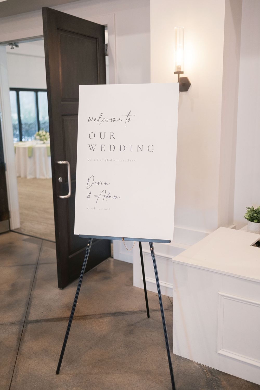 Elegant white wedding welcome sign on easel reading \"Welcome to Our Wedding\" displayed at venue entrance.