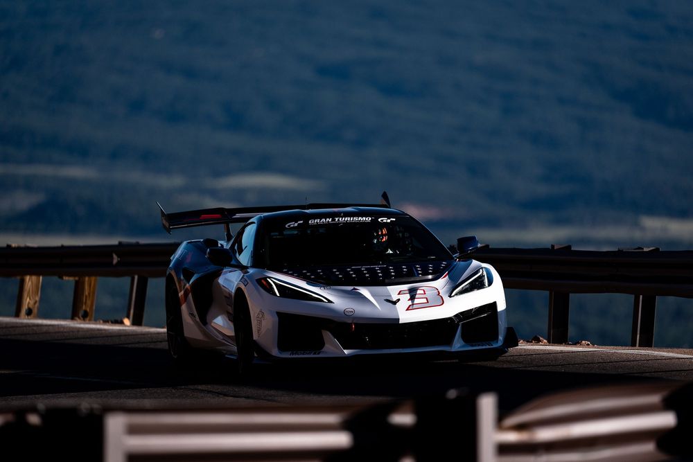 A silver Corvette Z06 race car navigates a mountain road at Pikes Peak International Hill Climb.