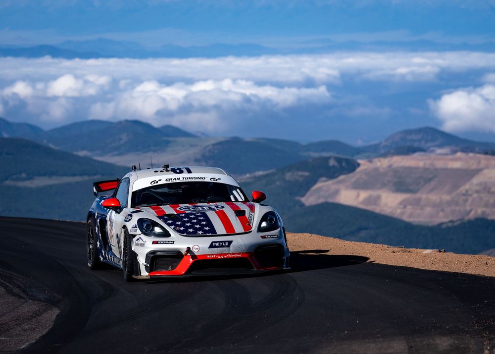 Porsche race car with American flag livery competing at Pikes Peak Hill Climb above the clouds.