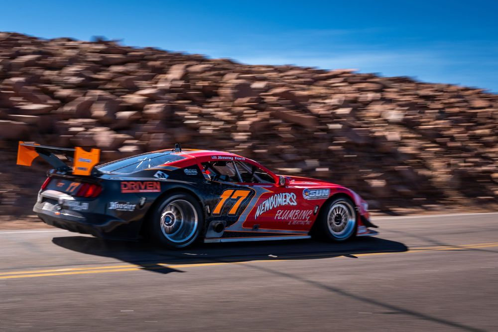Red and black race car number 17 speeding on a mountain road at Pikes Peak Hill Climb race.