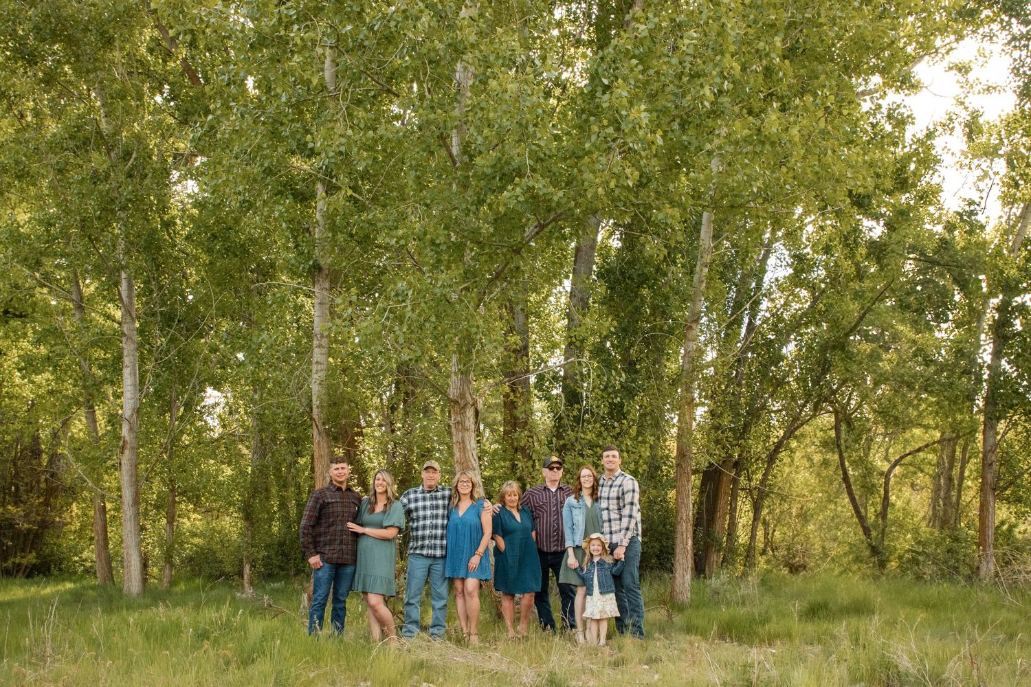 A family walks hand-in-hand through autumn woods, man carrying child, woman in plaid skirt, surrounded by golden foliage.
