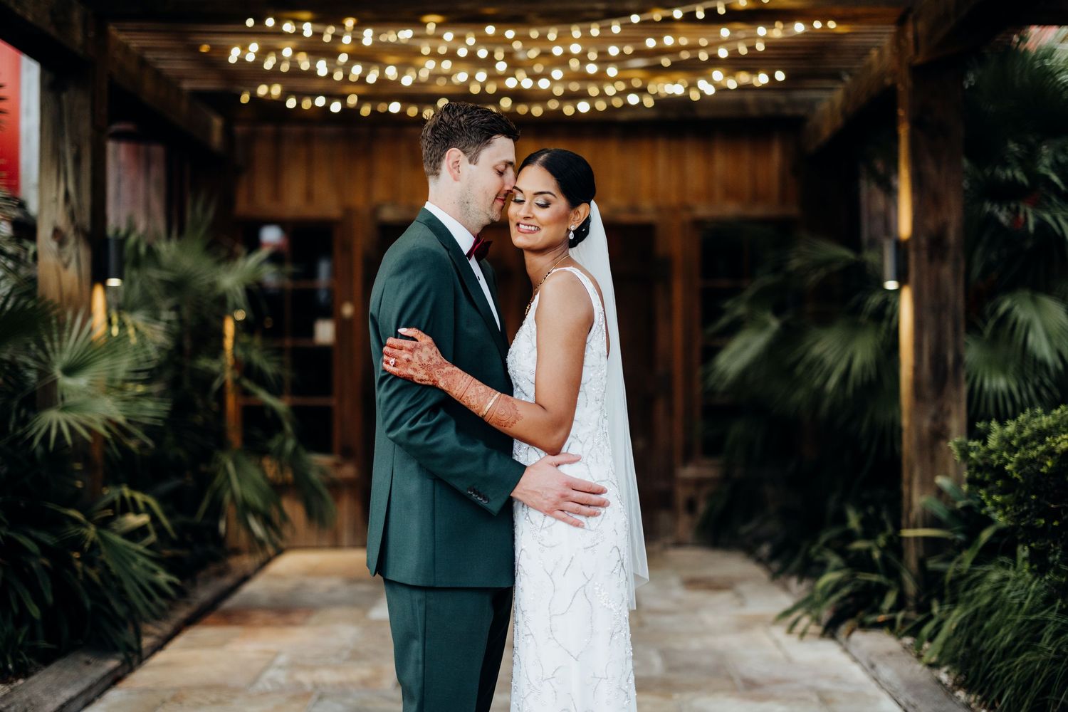 Bride and groom sharing a romantic dip kiss on white stairs of elegant Victorian mansion wedding venue.