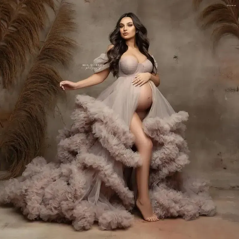 Pregnant woman in elegant taupe tulle maternity gown with dramatic ruffled skirt for a studio photoshoot.