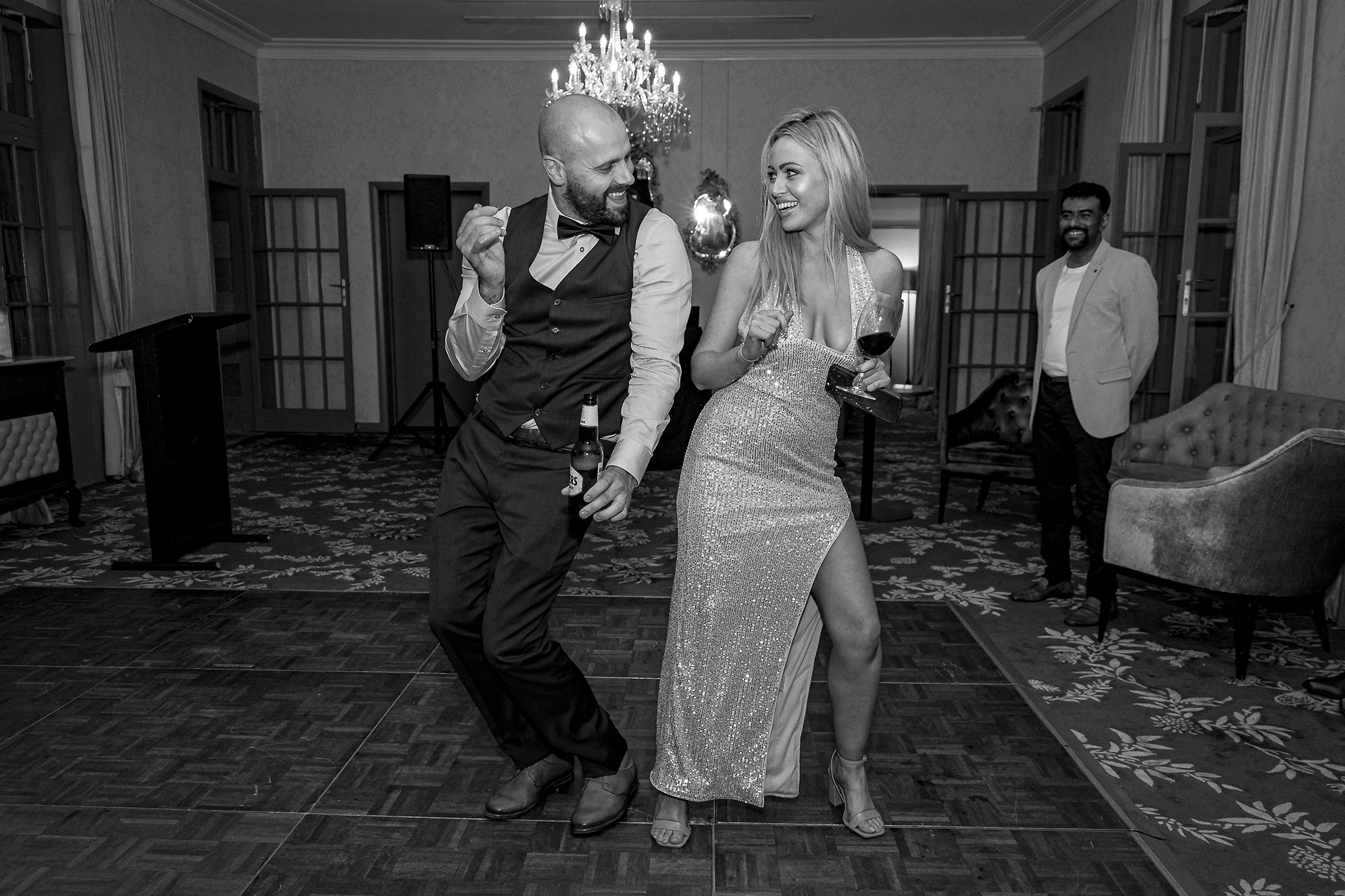 Sydney Event Photography - A couple dances energetically on a patterned carpet under a chandelier.