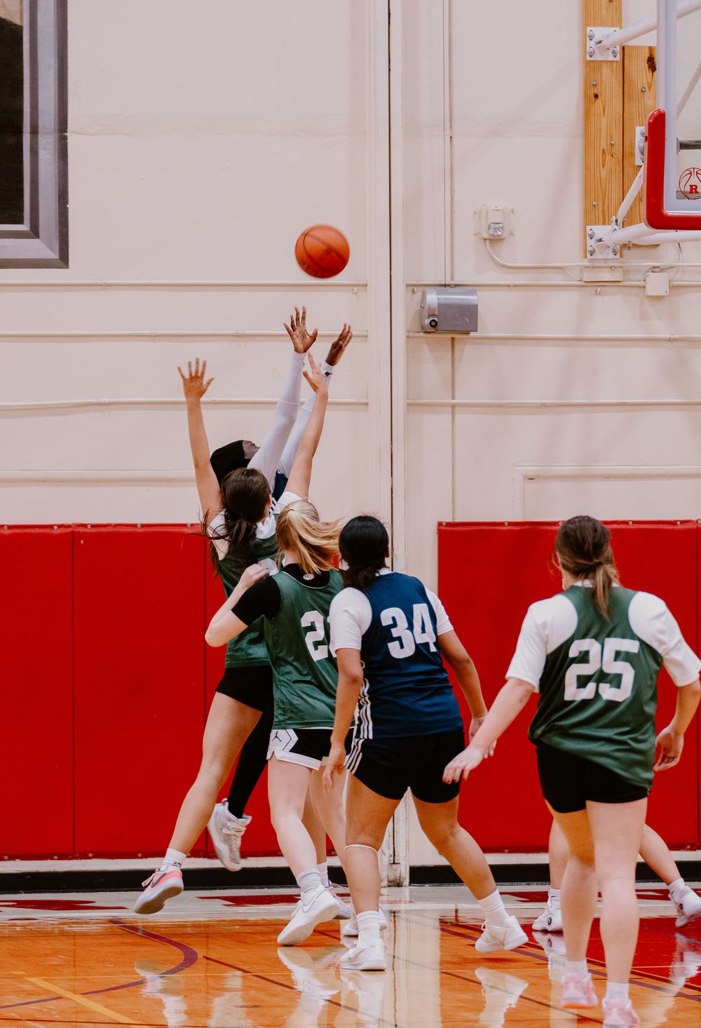 Players jump for basketball during tipoff with teammates watching.