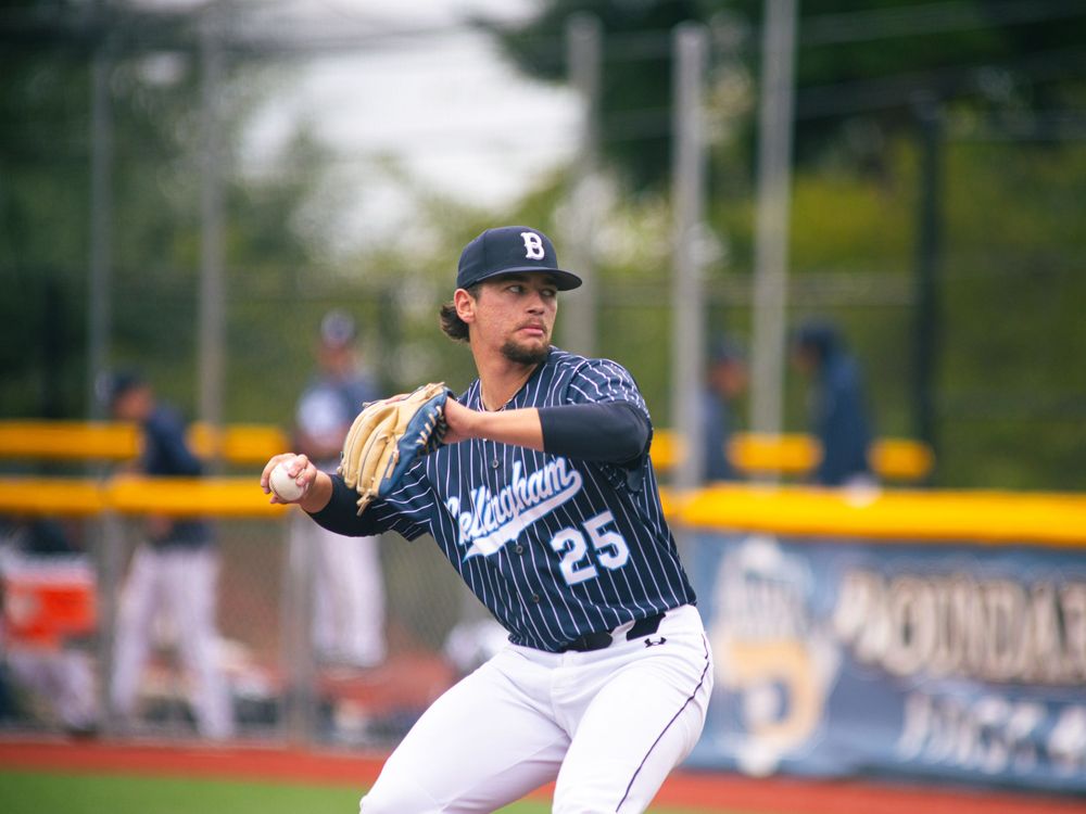 Baseball player in pinstripe uniform throws ball during game action.