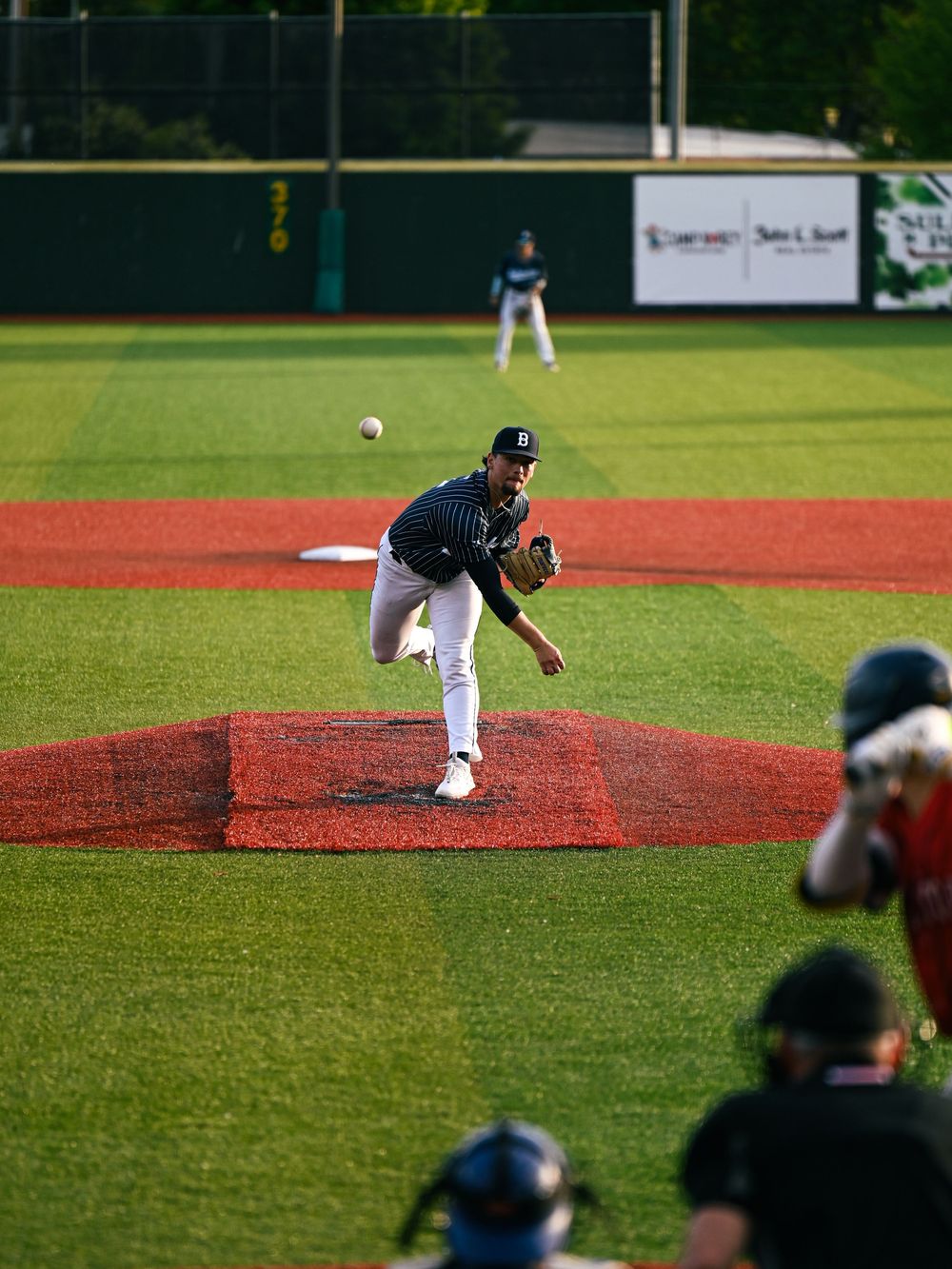 Baseball game action shot on field with spectators watching from bleachers.