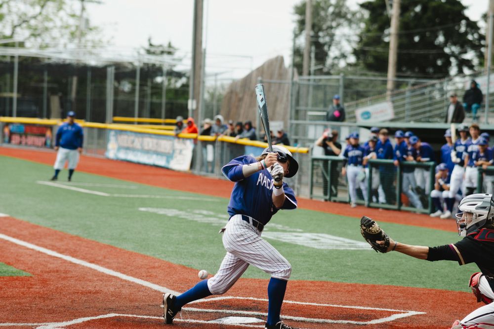 Baseball player sliding into home plate with catcher ready to make the play.