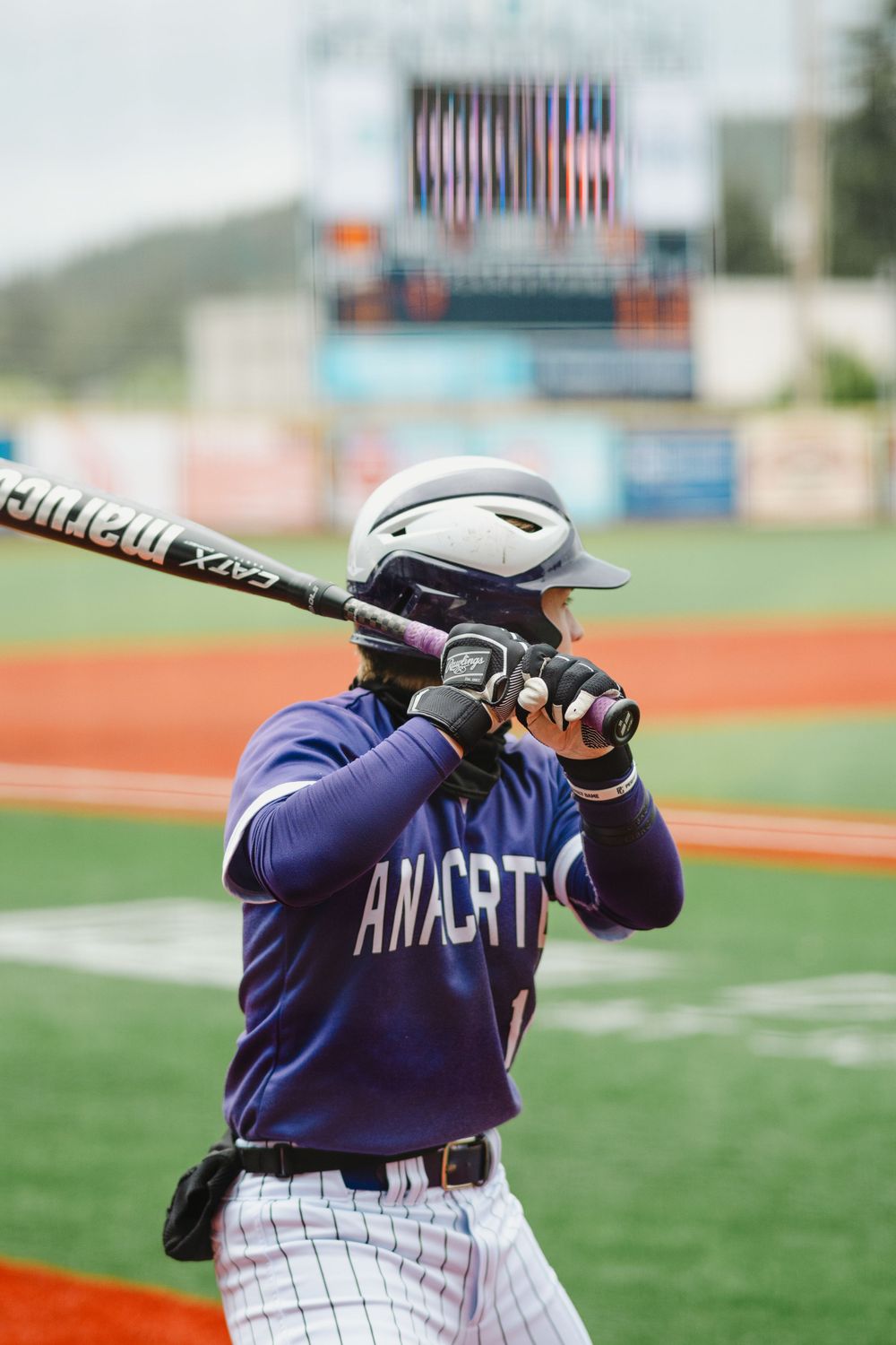 Baseball player in batting stance wearing blue Anacortes uniform and helmet.