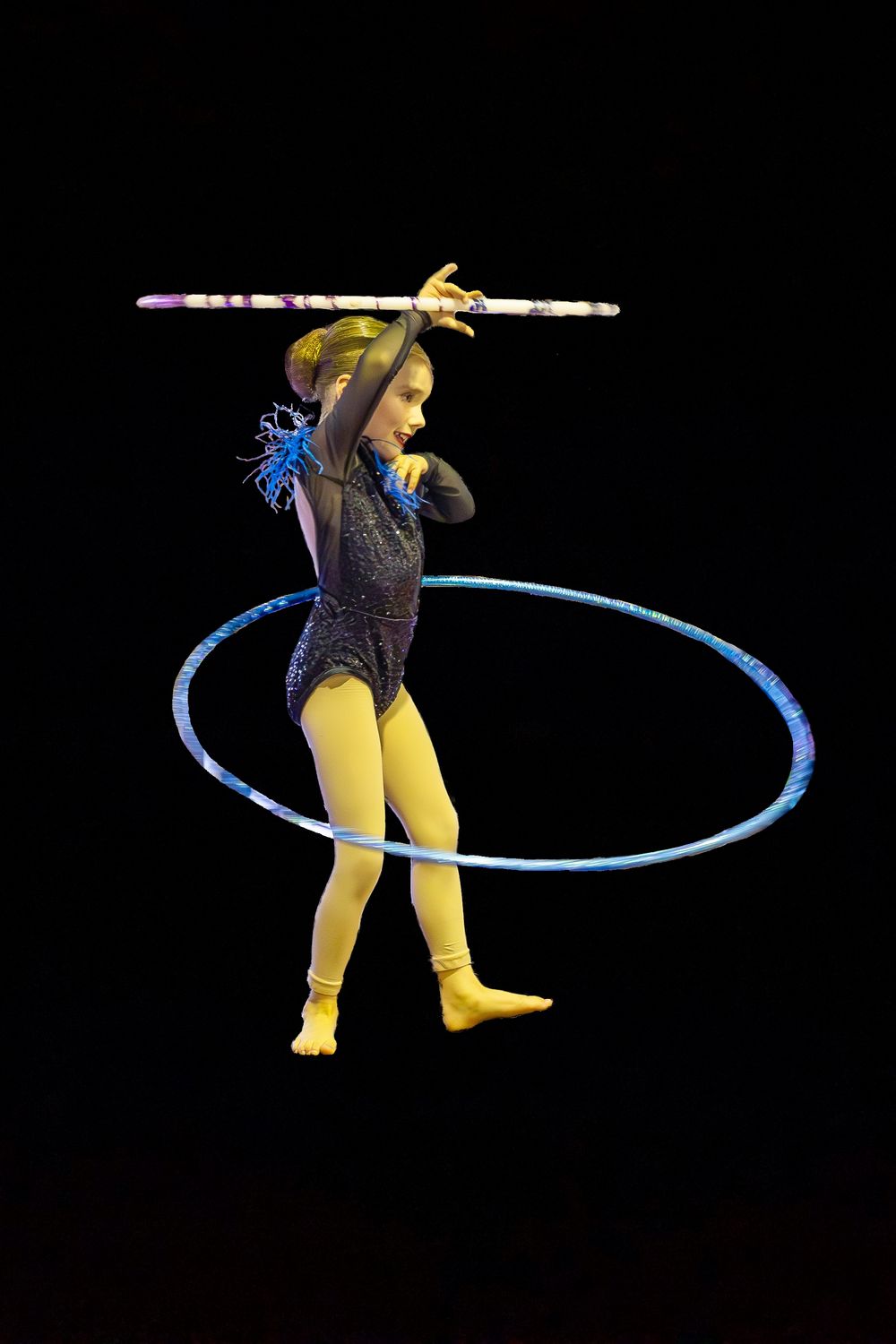 Focal Point Images
Circus performer in yellow tights balances with hoop and baton against black background.