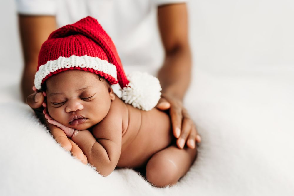 A newborn baby sleeping peacefully on white blankets while wearing a red and white Christmas santa hat.
Rashinphotography-Nova photographer