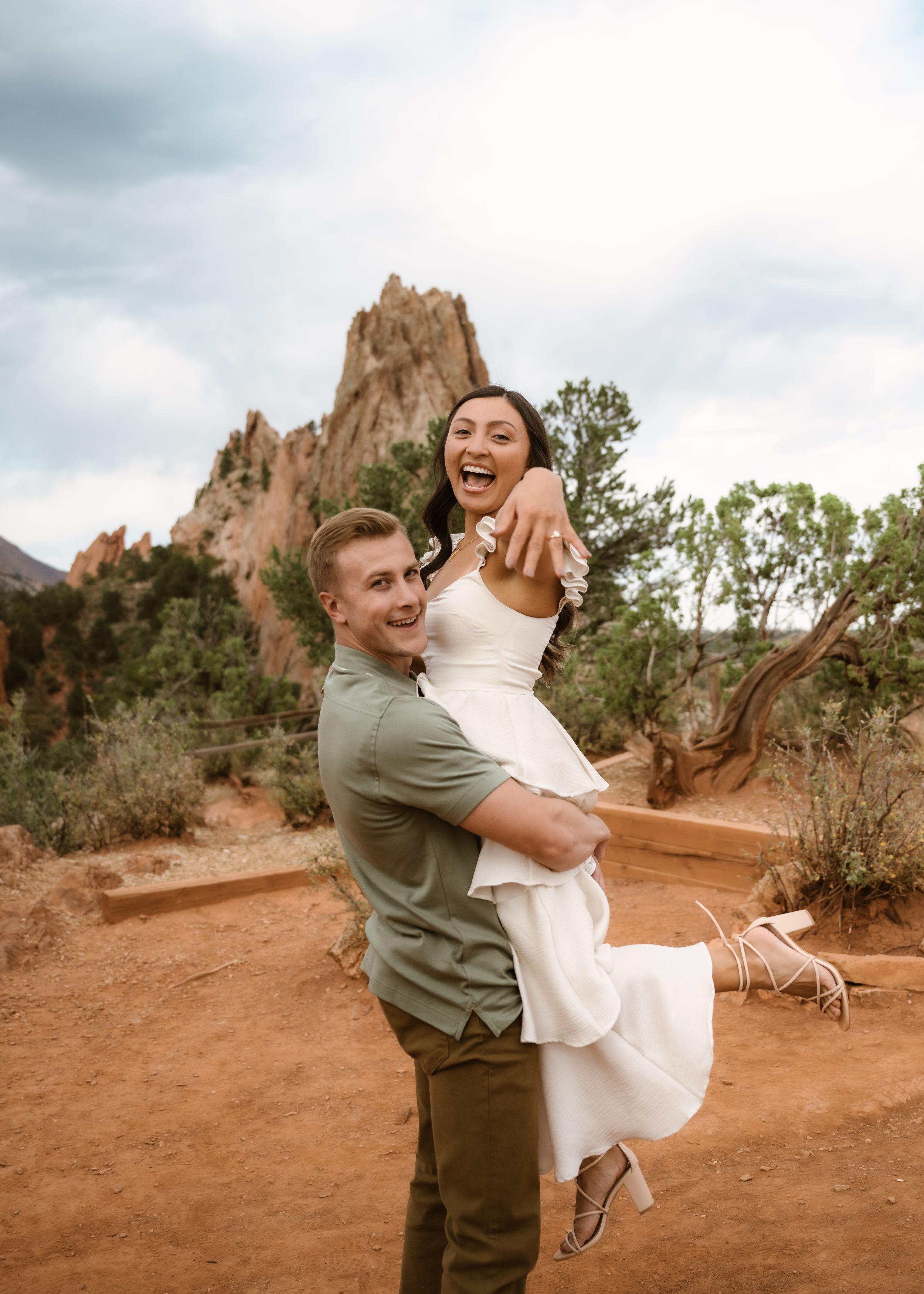 A couple dances and spins playfully against red rock formations in a desert landscape.