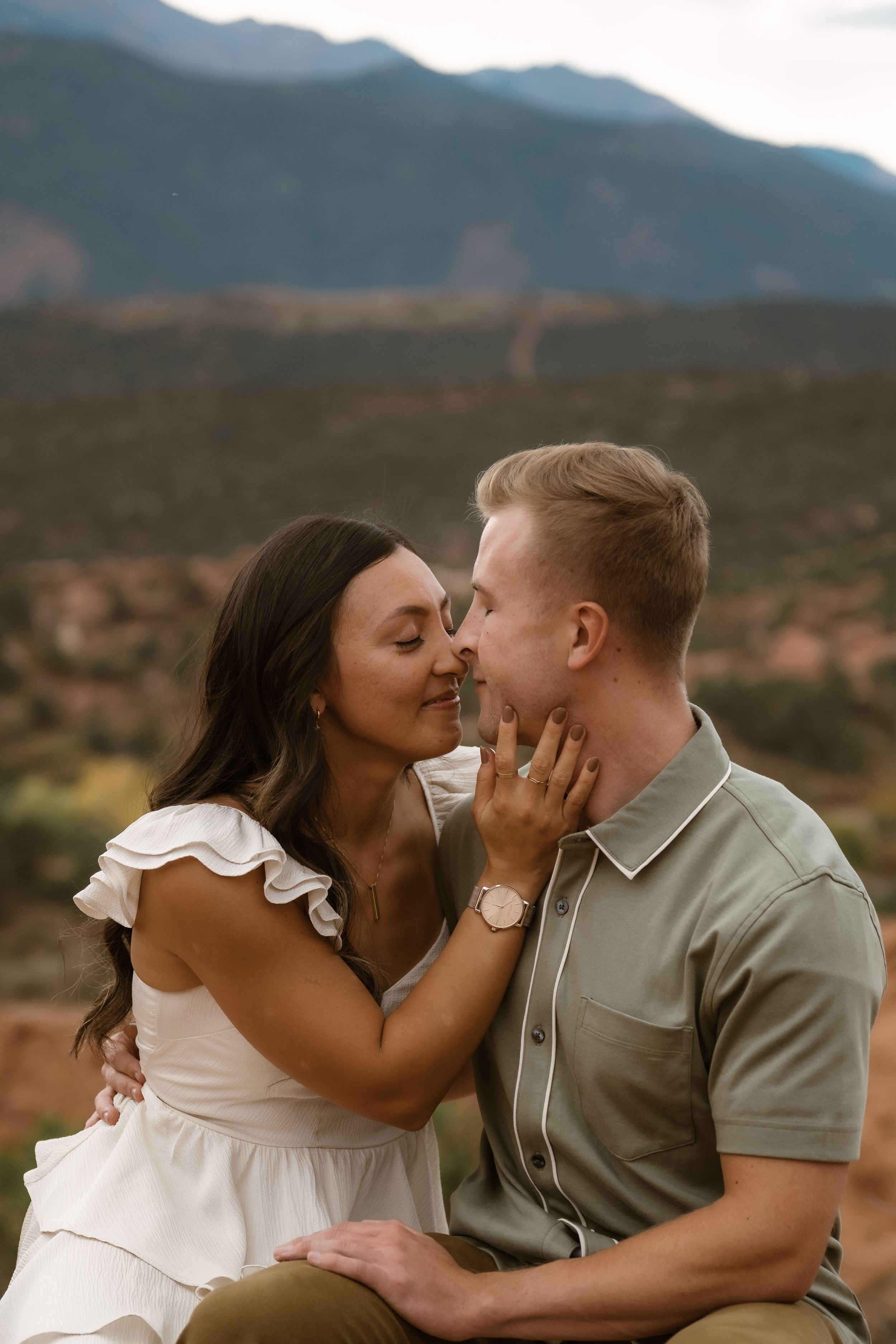 An intimate moment between a couple against a backdrop of mountains and desert landscape.