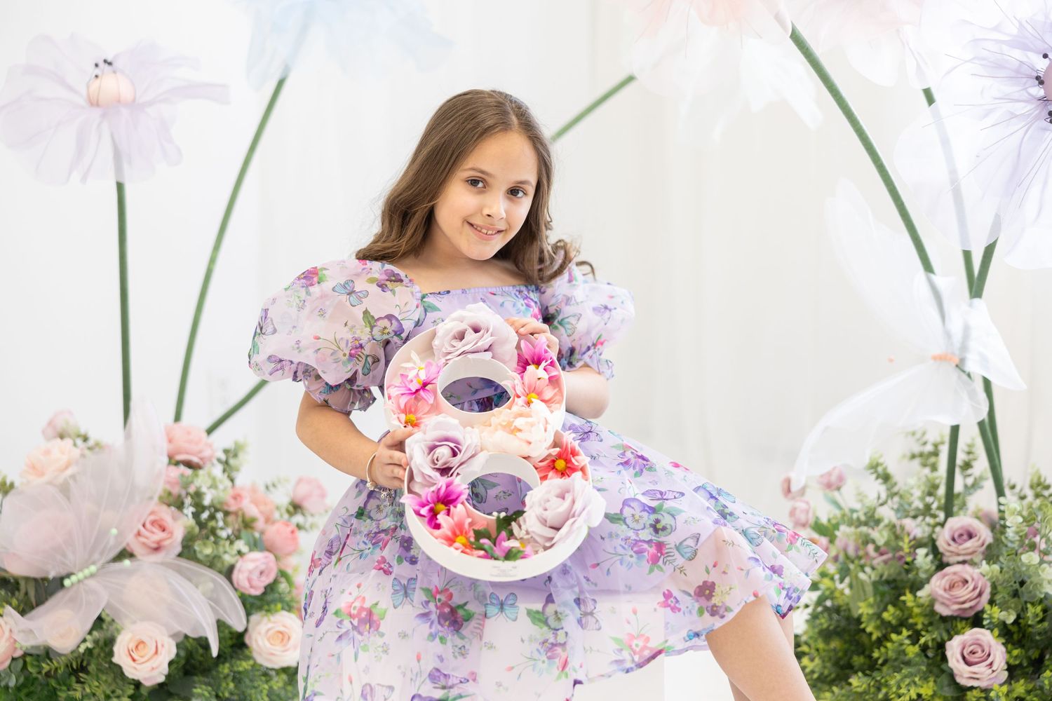 Floral spring photoshoot featuring a purple floral dress and decorative number 8 against a garden backdrop.