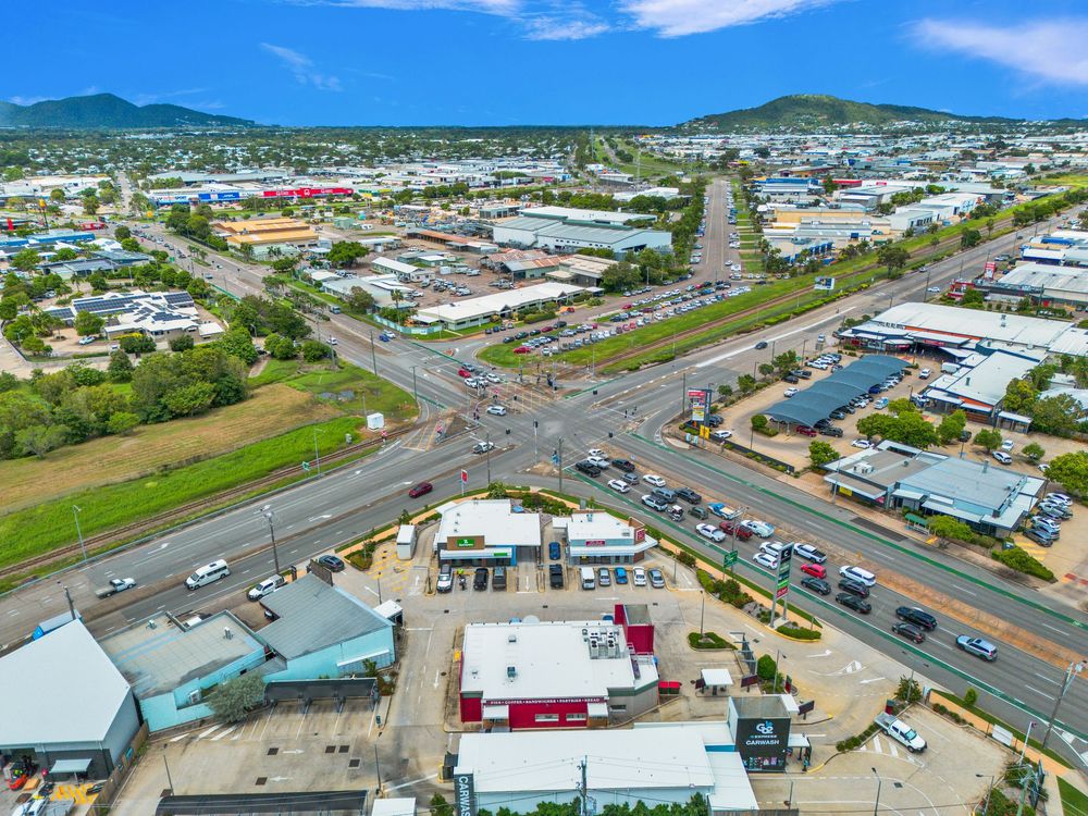 Aerial panoramic view of coastal town development with commercial buildings and roads under blue sky.