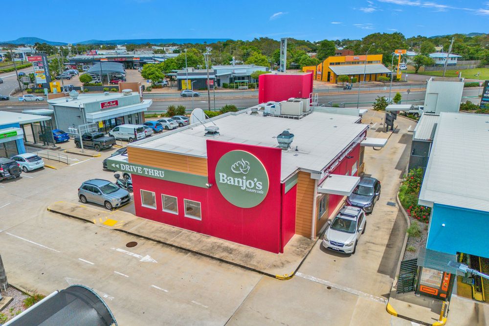 Aerial view of colorful commercial buildings and parking lots along a street in a small business district.