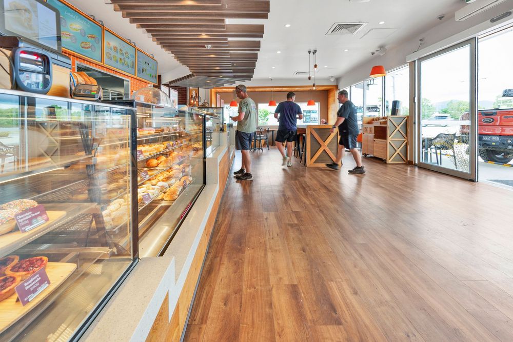 Long bowling alley lanes with wooden floors and modern scoring displays stretch toward large windows at the end of the venue.