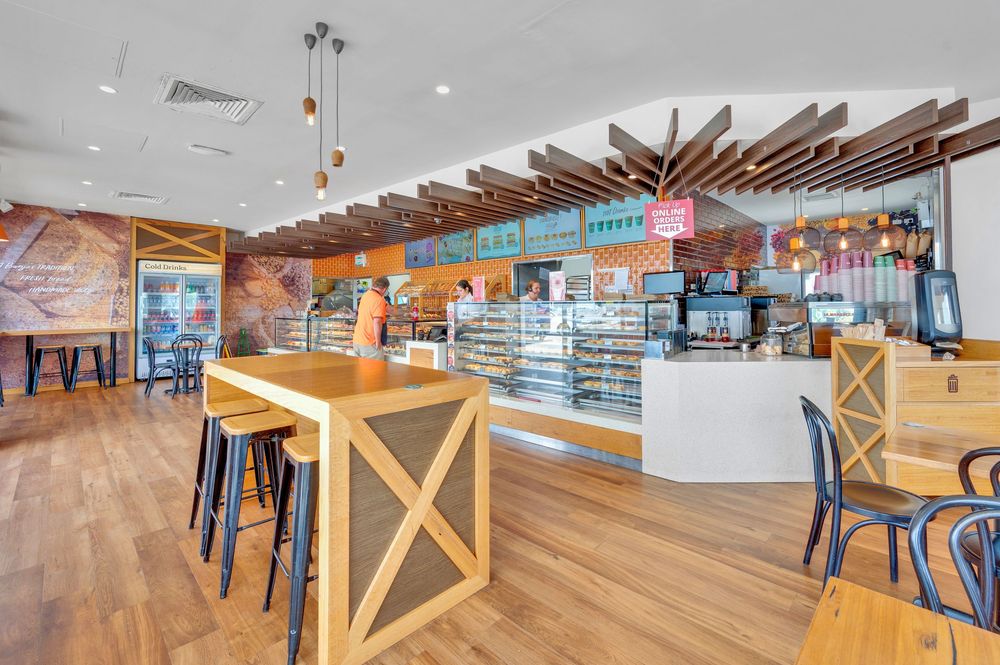 Modern cafe interior with wooden slat ceiling, pendant lights, and comfortable seating arrangements.