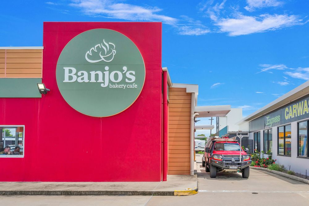 Exterior view of a strip mall building with Banjo's signage and orange accents against a bright blue sky.