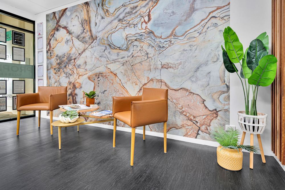 Modern office interior with marble walls, tan leather seating, and potted plants creates an elegant workspace design.
