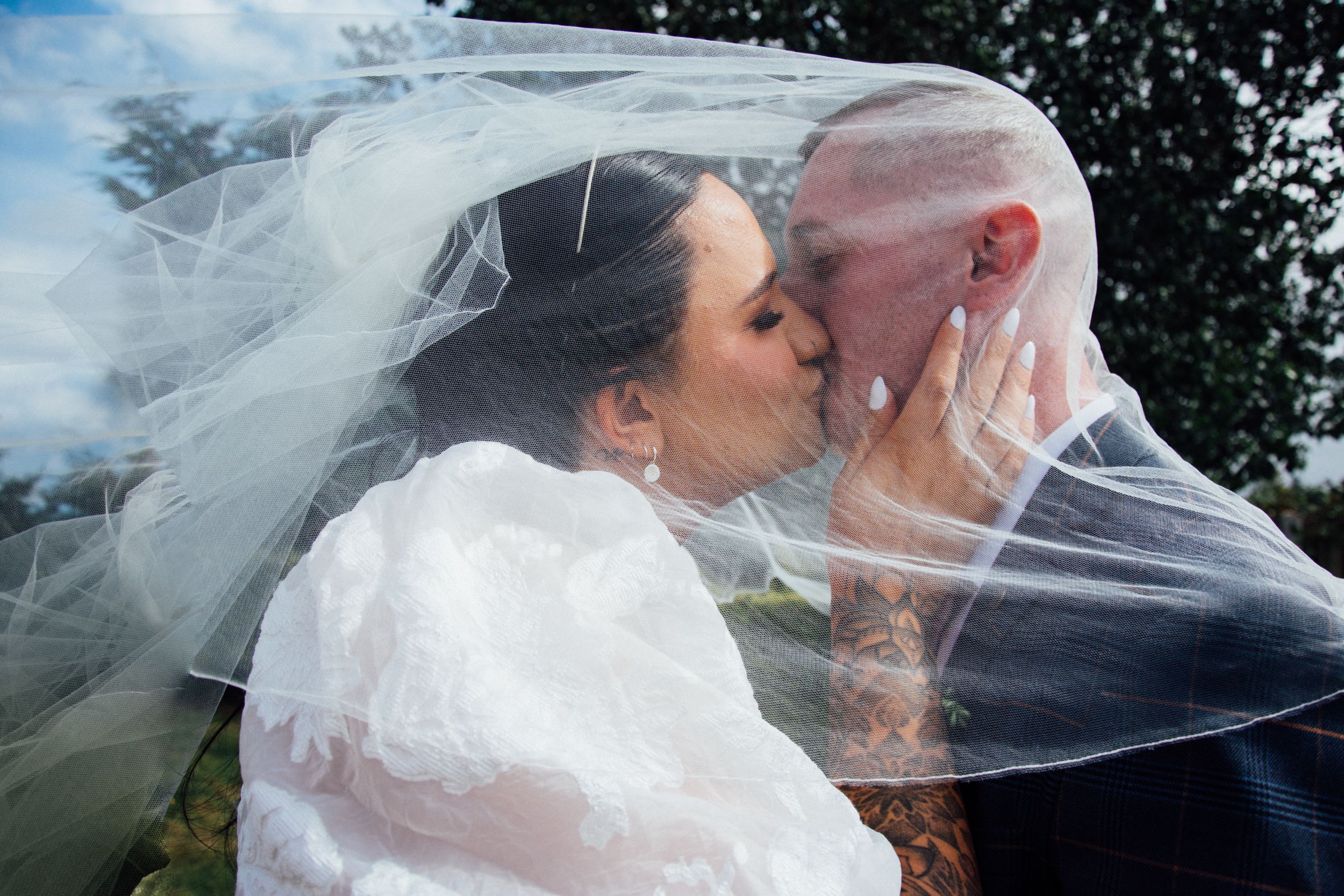 Romantic wedding portrait with couple embracing under flowing veil.