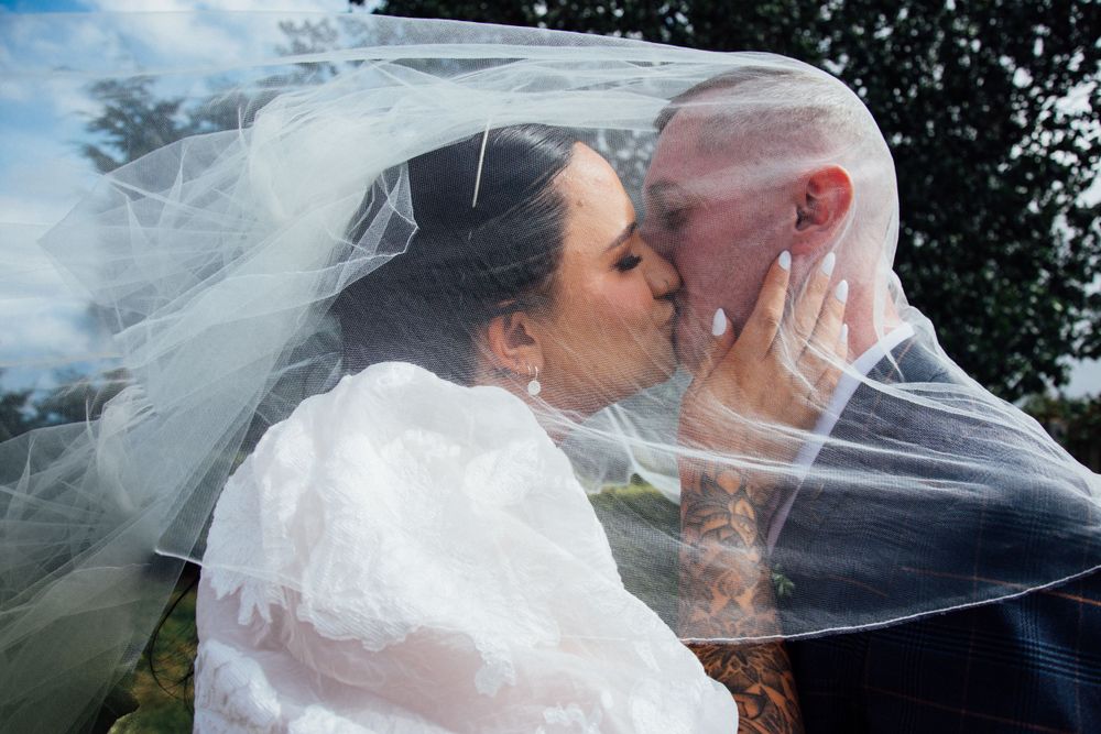 Romantic wedding portrait with couple embracing under flowing veil.