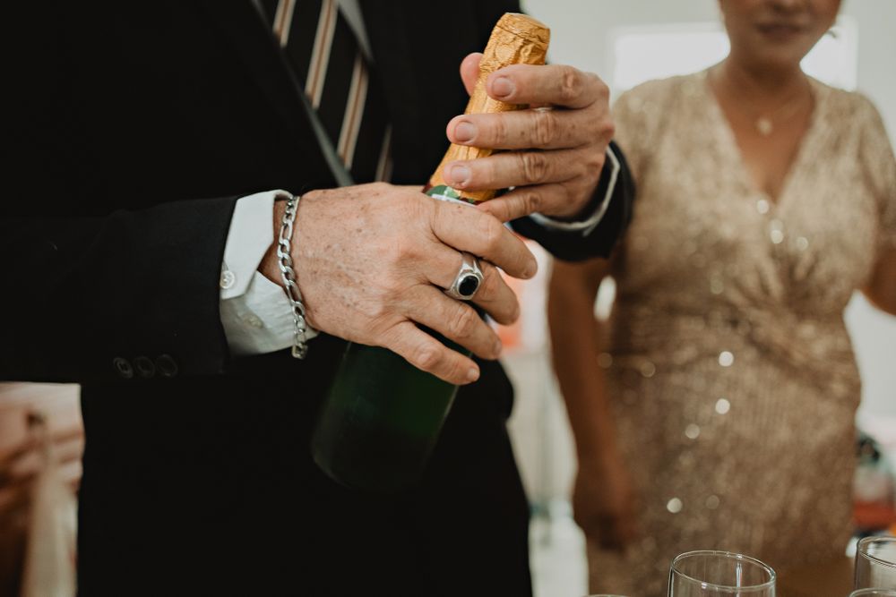 The father uncorking a bottle, preparing to toast during this beautiful destination wedding