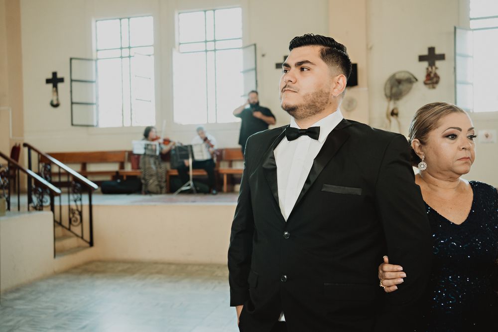 The groom waiting for the bride at the altar alongside his mother, a moment filled with emotion